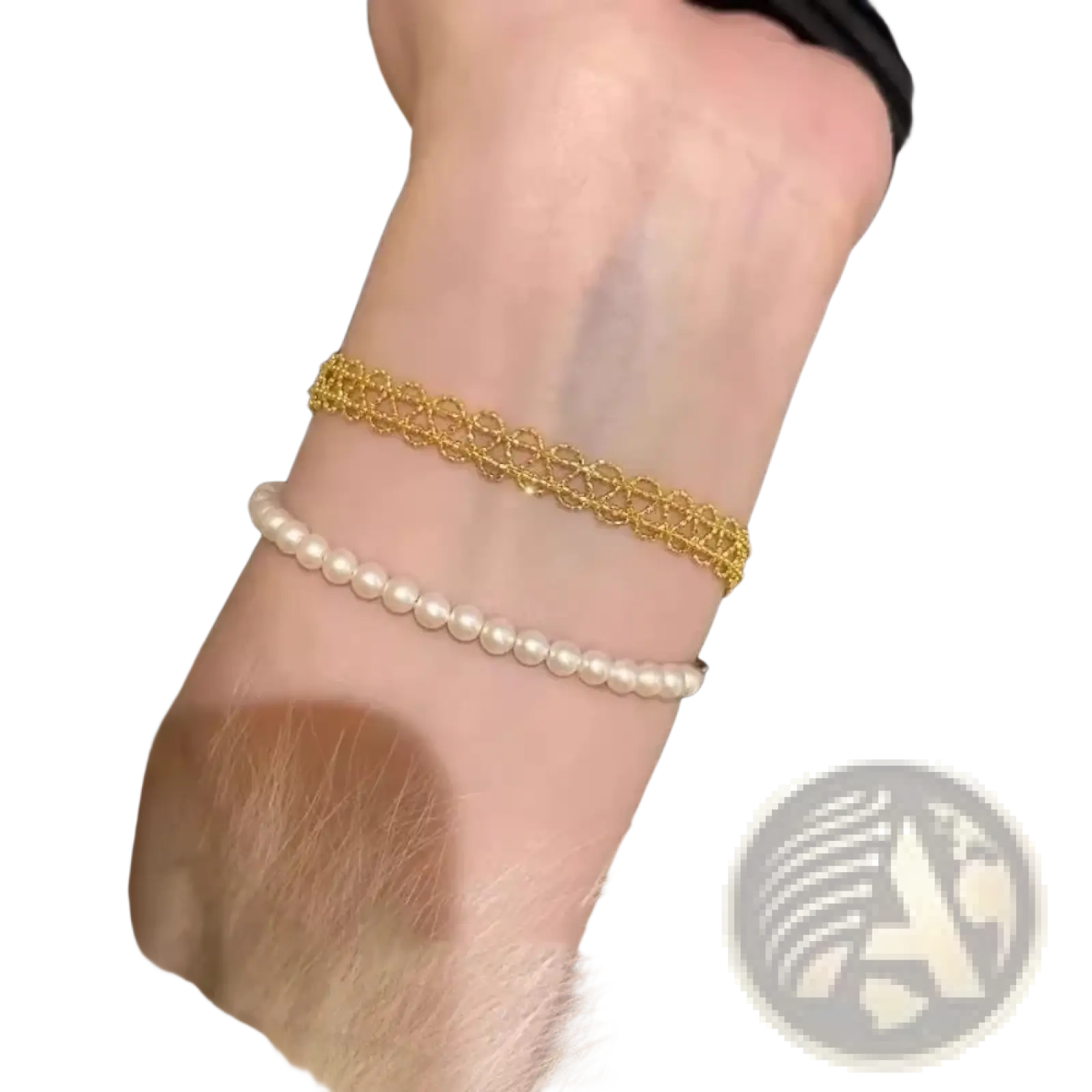 Metal lace bracelet in gold with intricate lace-like design worn alongside white pearl strand fashion jewelry