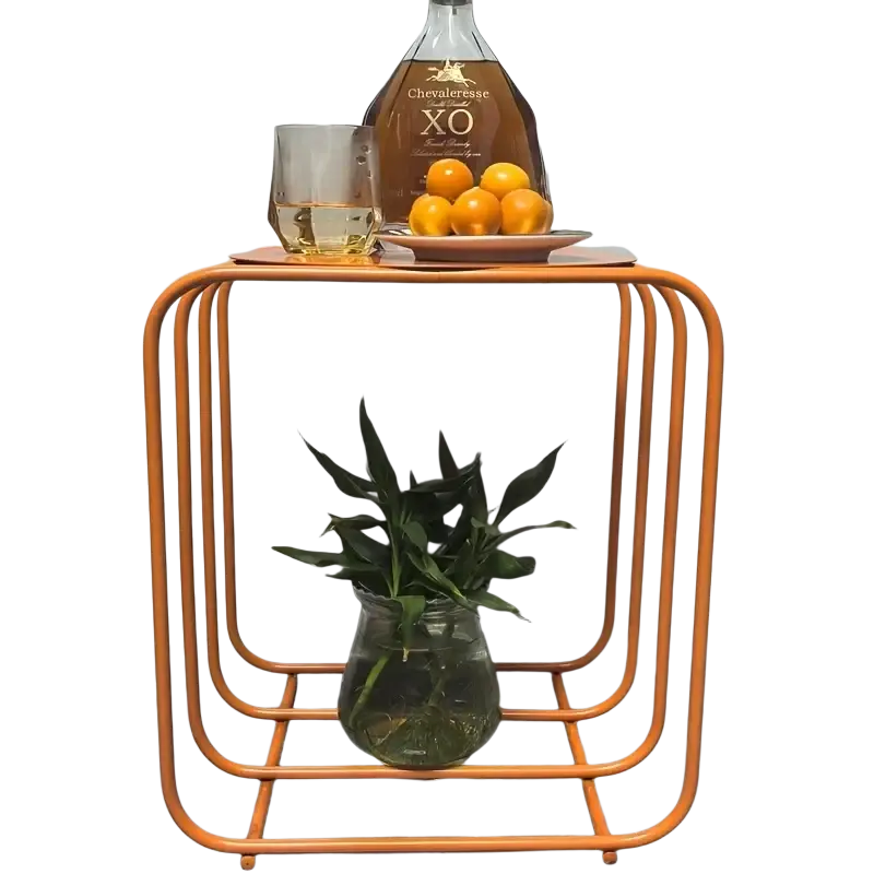 Orange metal side table with geometric frame design and glass vase on lower shelf for minimalist storage and magazine rack