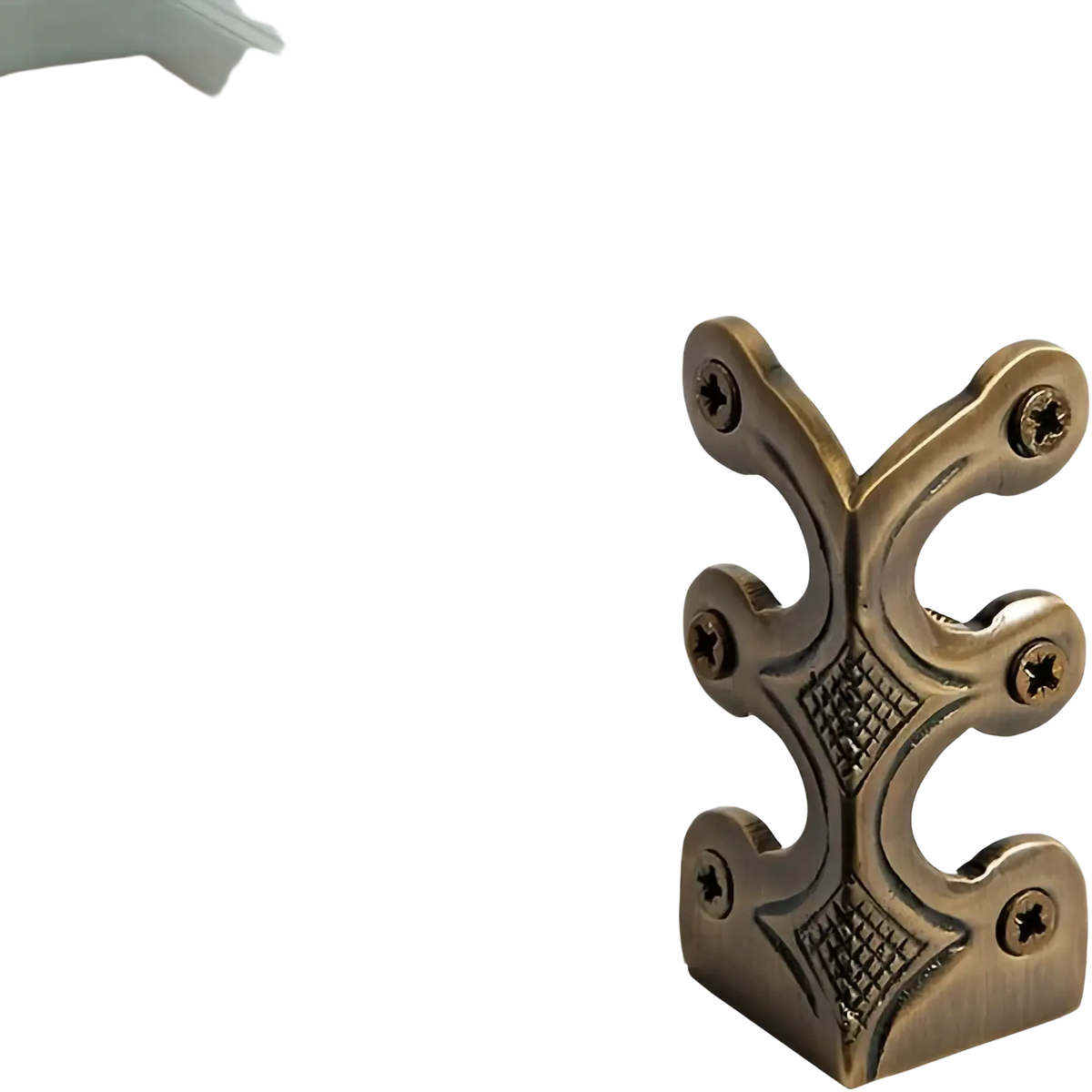 Antique brass-finished metal corner protector with ornate symmetrical design and four screw holes for skirting boards