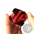 A glossy red metallic fidget cube with angular interlocking segments for stress relief toy use