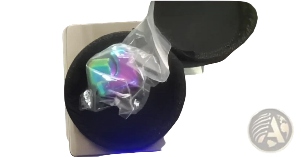 A holographic iridescent metallic fidget cube rainbow stress relief toy wrapped in clear plastic on a digital scale
