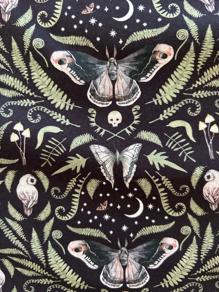 Dark fabric blouse with vintage bow featuring a moth skull and moon pattern in muted greens and creams