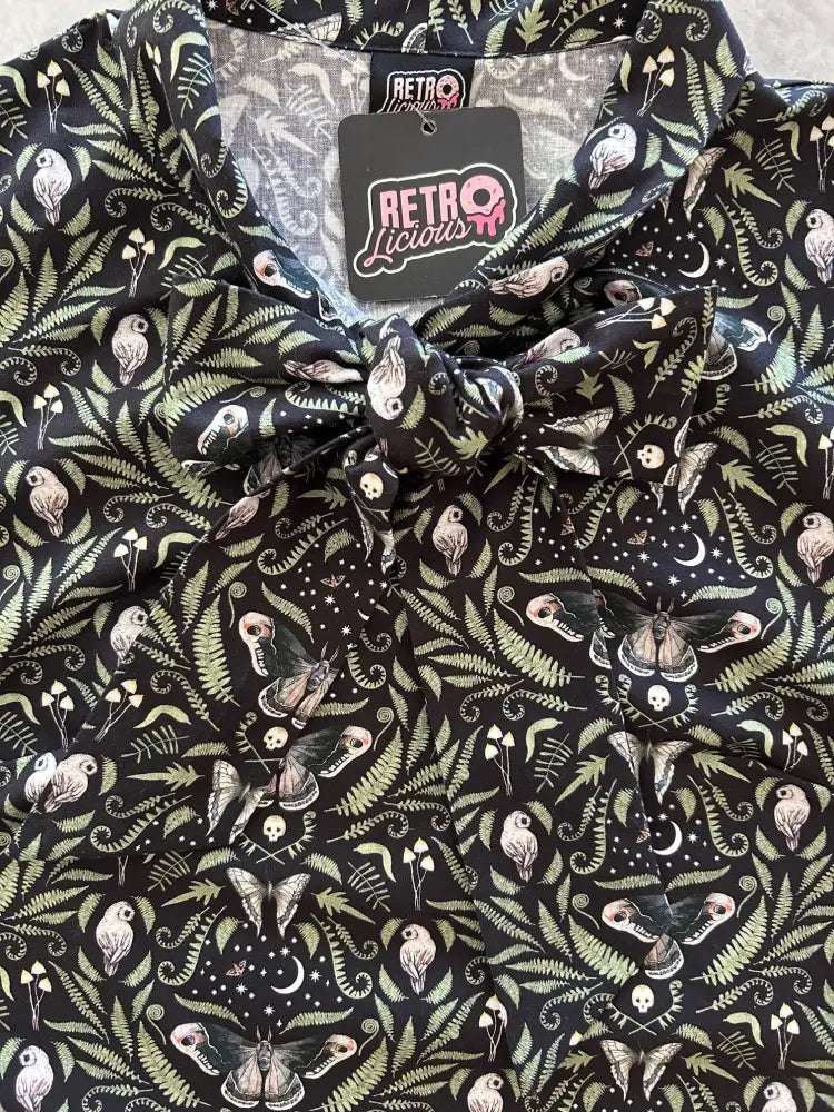 Black button-up blouse with whimsical owl butterfly skull fern and moon pattern in muted greens and pinks midnight moth design