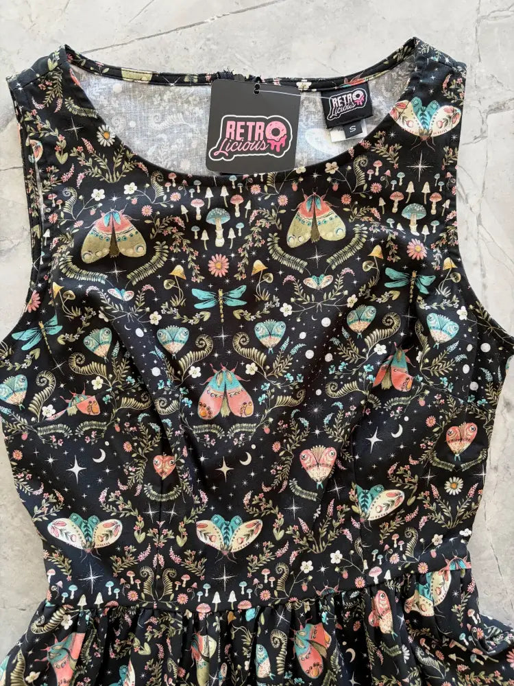 A black sleeveless cotton a-line midi dress with a whimsical midnight butterfly print in pastel pinks teals and golds