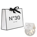 White paper shopping bag with black trim satin ribbon bow and n°30 logo for milestone birthday gift with card