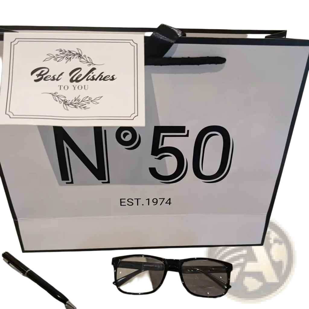 Black-framed rectangular glasses with clear lenses resting on reflective surface in milestone birthday gift bag set