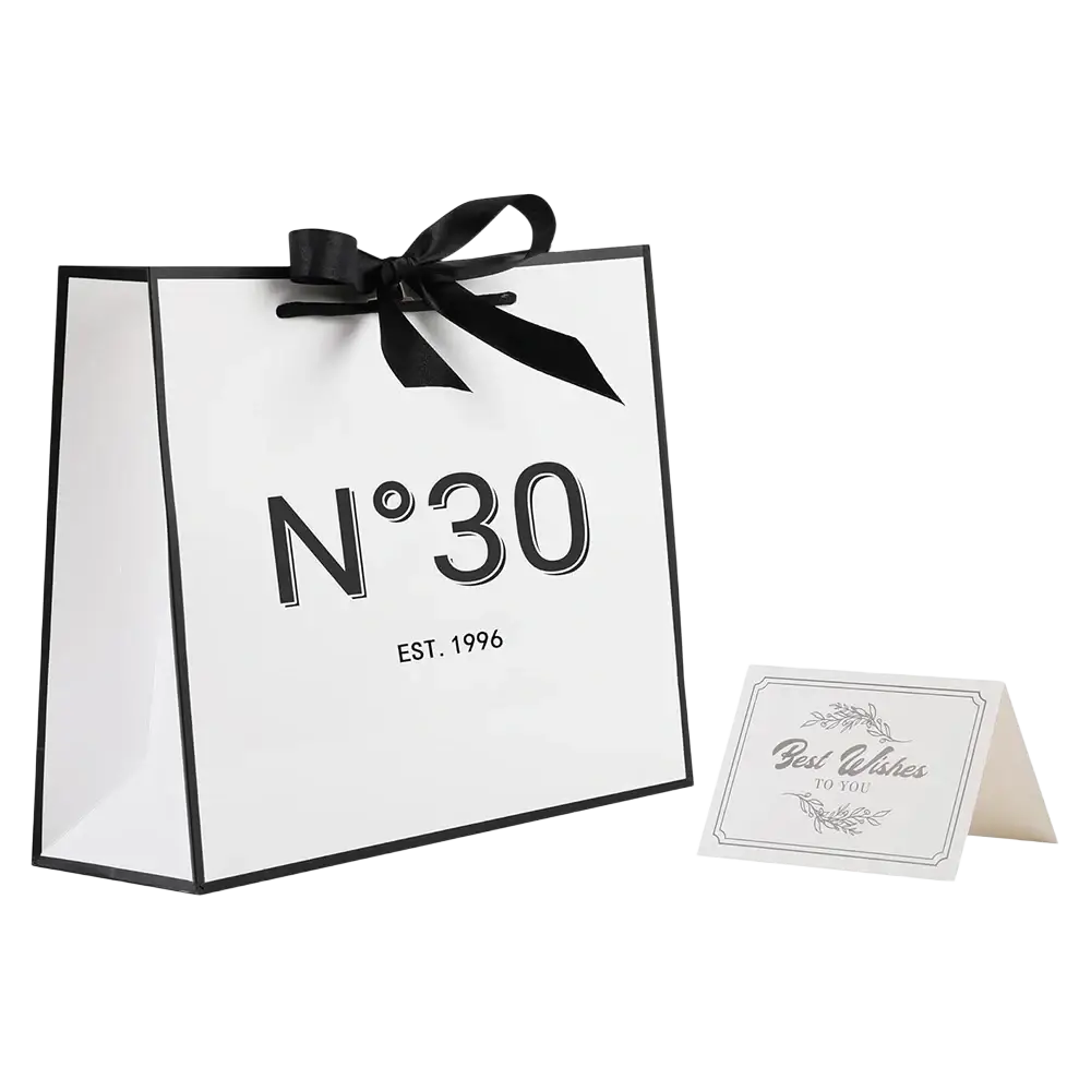 White paper shopping bag with black trim satin ribbon bow and n°30 logo for milestone birthday gift with card