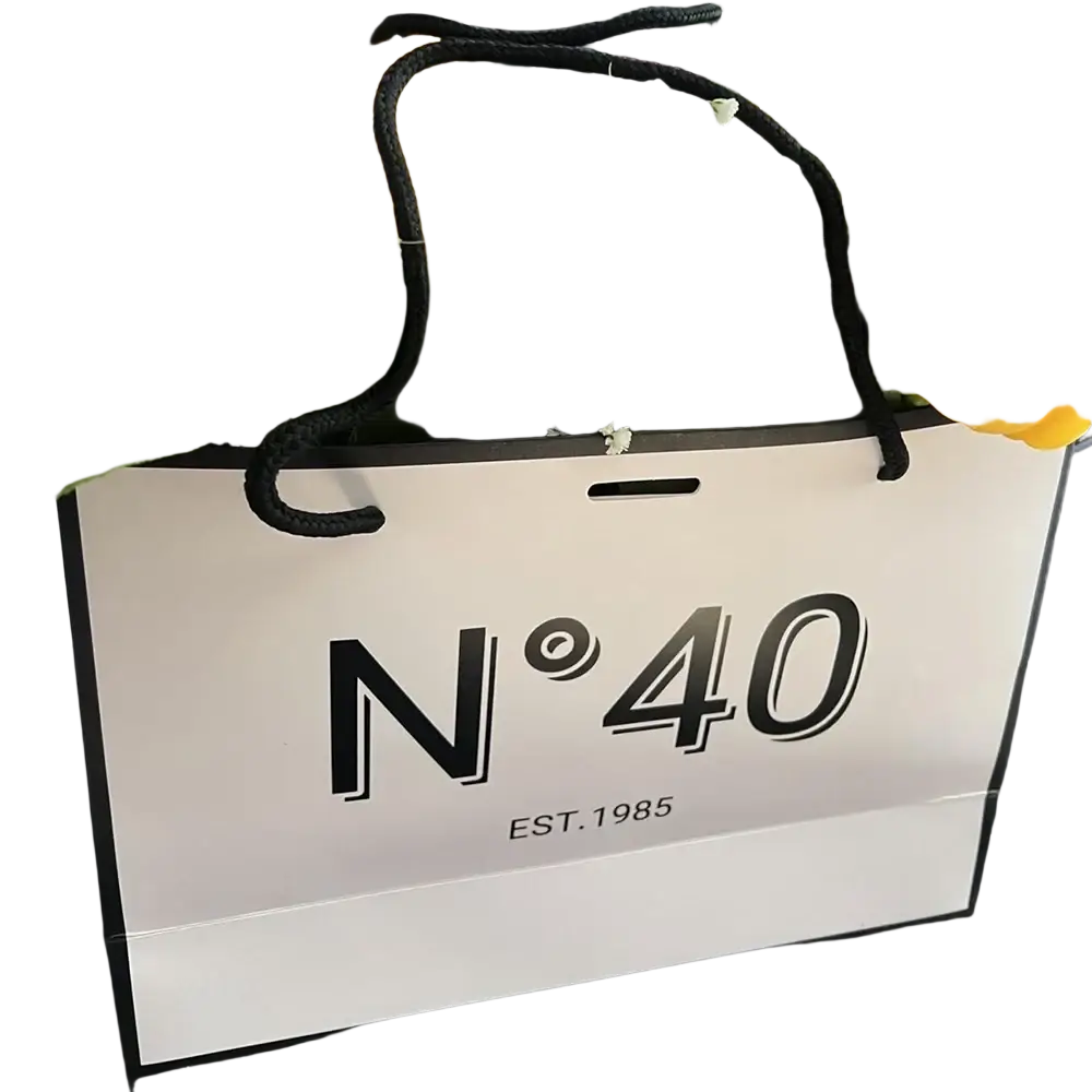 White paper shopping bag with black handles and bold n40 branding for milestone birthday gift with card and ribbon