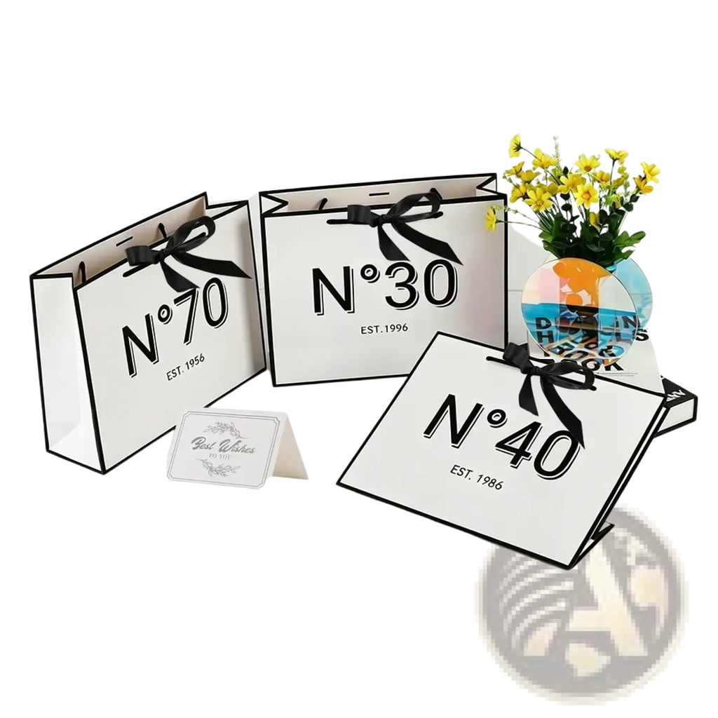 White paper shopping bags with black printed numbers and est dates tied with black ribbon bows for milestone birthdays