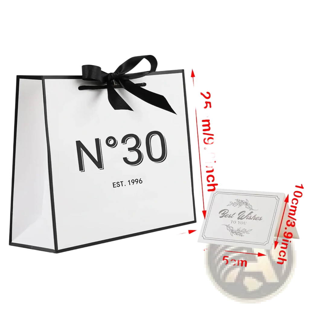 White paper shopping bag with black trim and satin ribbon bow featuring n°30 est for milestone birthday gift use
