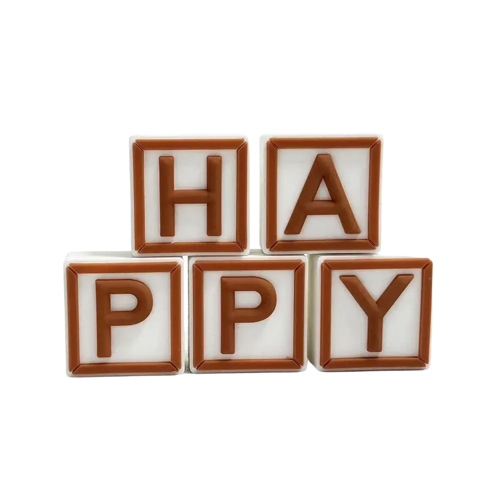 Mini bear cake topper set with white and brown plastic letter blocks spelling happy in two rows on plain surface