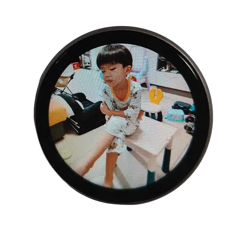 Circular black-framed mini gadget smart desktop companion with data cable displaying photo of boy in patterned pajamas on stool
