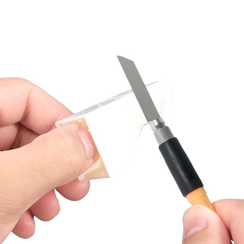 White plastic model car body being shaped with a precision knife from mini hand saw kit for precision model making