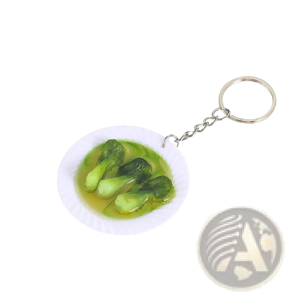 Miniature food keychain with a white plate of green bok choy leaves in light yellow broth on a silver chain ring