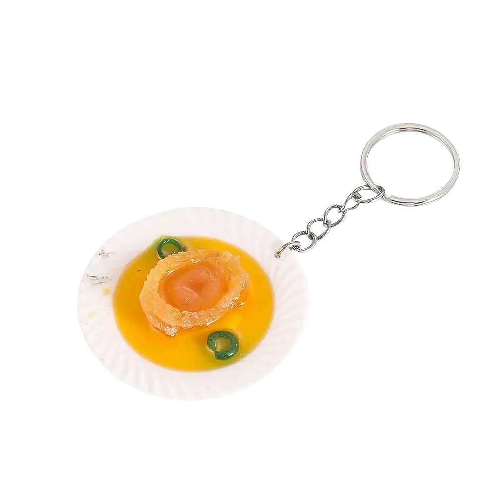 Miniature food keychain featuring a detailed abalone replica on a white paper plate with yellow sauce and garnish
