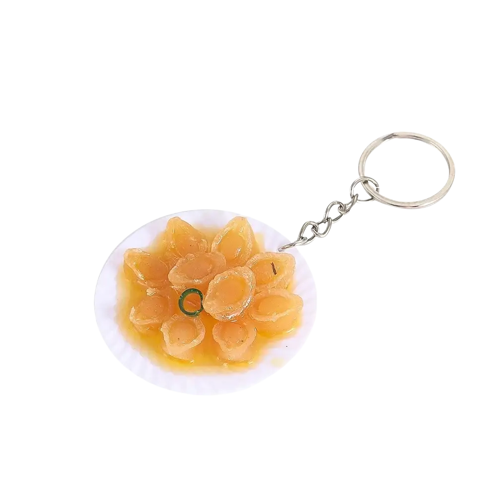 Miniature food keychain featuring golden-brown dumplings on a white plate attached to a silver chain and ring