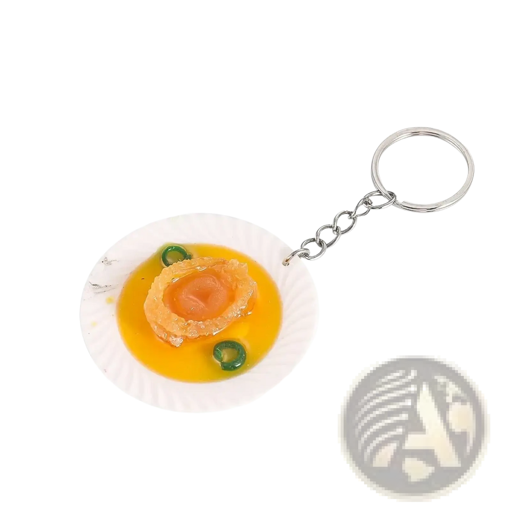 Miniature food keychain featuring a detailed abalone replica on a white paper plate with yellow sauce and garnish