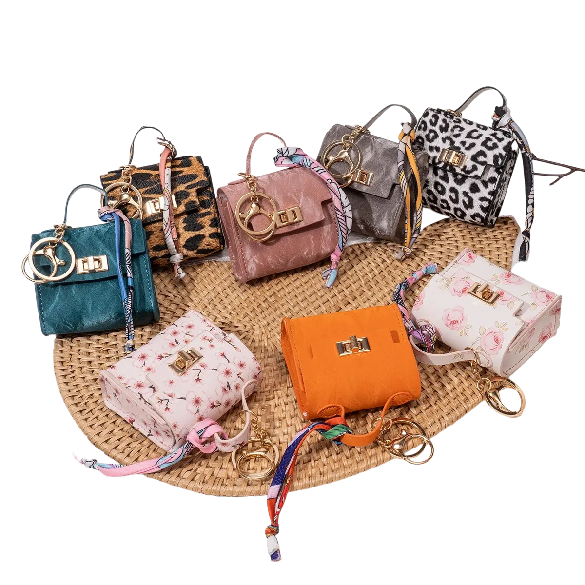 A collection of colorful miniature handbag keychains with gold tone clasps and silk scarf accents