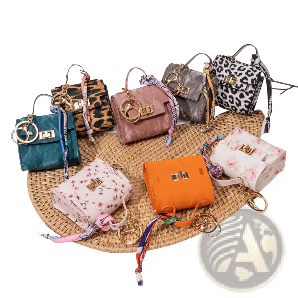 A collection of colorful miniature handbag keychains with gold tone clasps and silk scarf accents