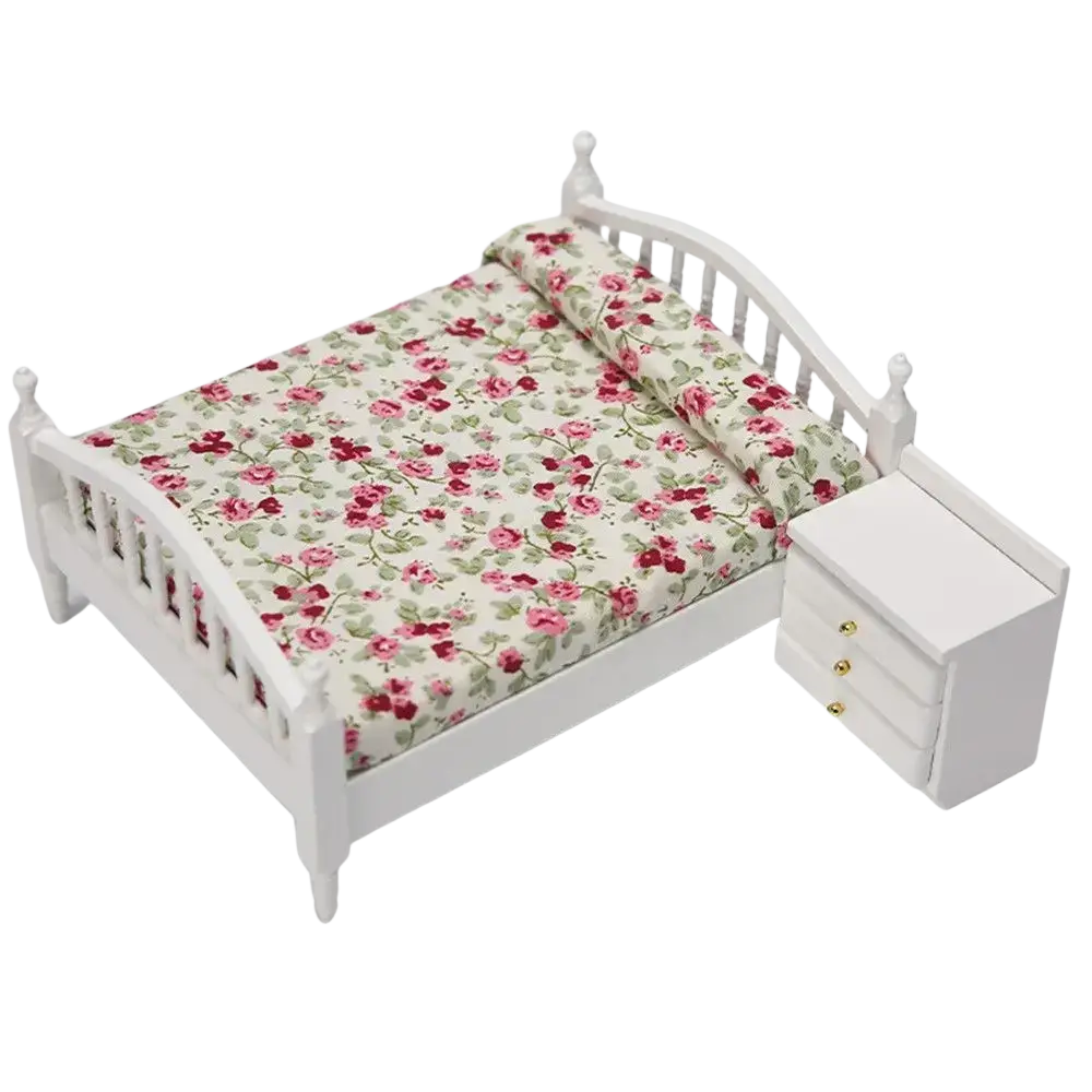 Miniature wooden dollhouse bed in white with a floral-patterned mattress featuring pink roses on cream background