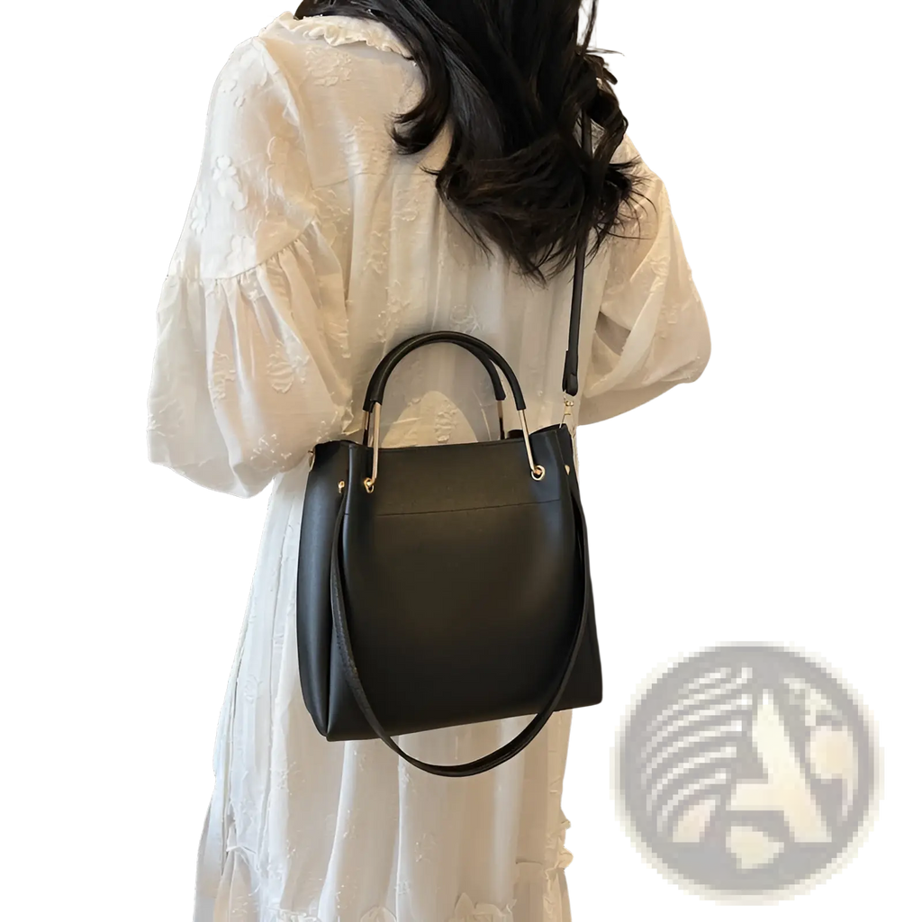 Minimalist black leather bucket bag with gold-tone hardware, top handle, and detachable strap for versatile use