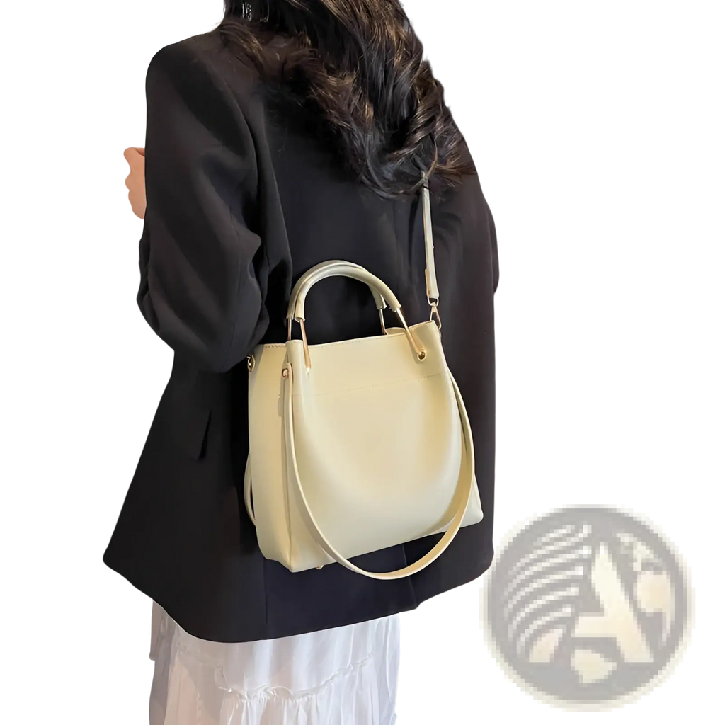 Minimalist cream-colored leather bucket bag with top handle and detachable shoulder strap for versatile use
