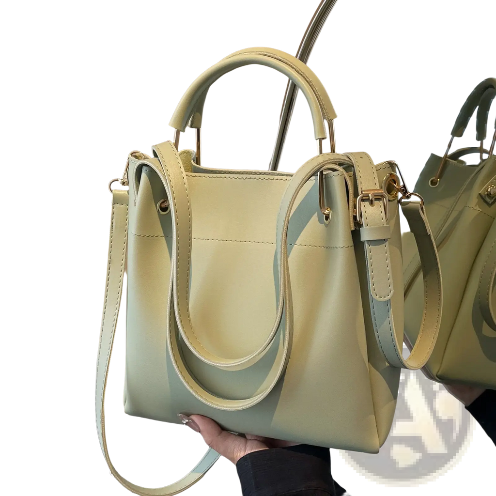 Minimalist leather bucket bag in pale green with structured handles and detachable shoulder strap
