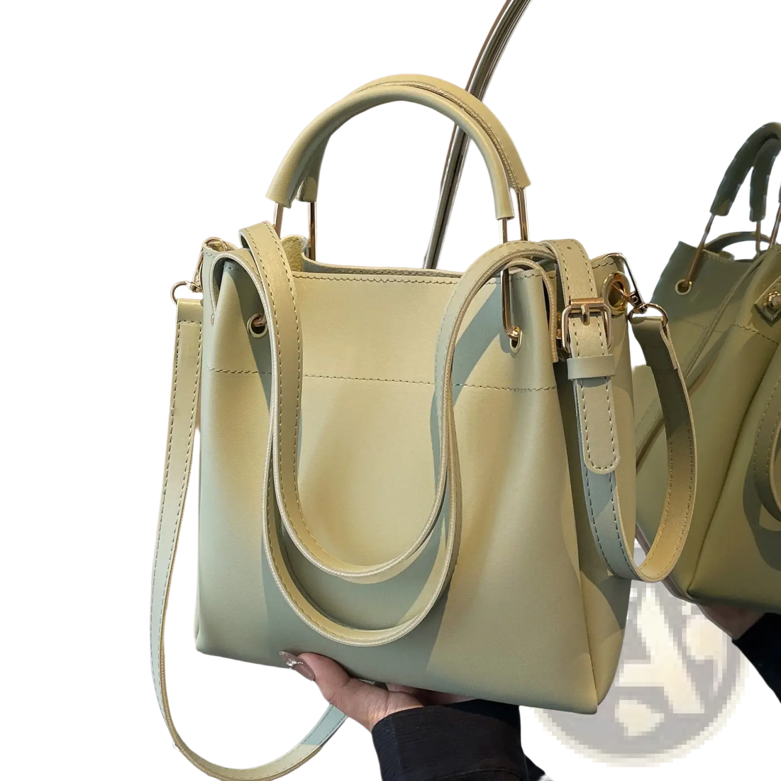 Minimalist leather bucket bag in pale green with structured handles and detachable shoulder strap