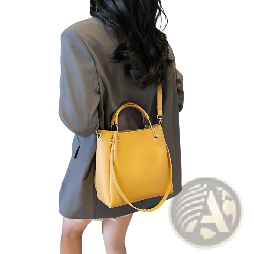 A vibrant yellow minimalist leather bucket bag with top handles and a detachable shoulder strap