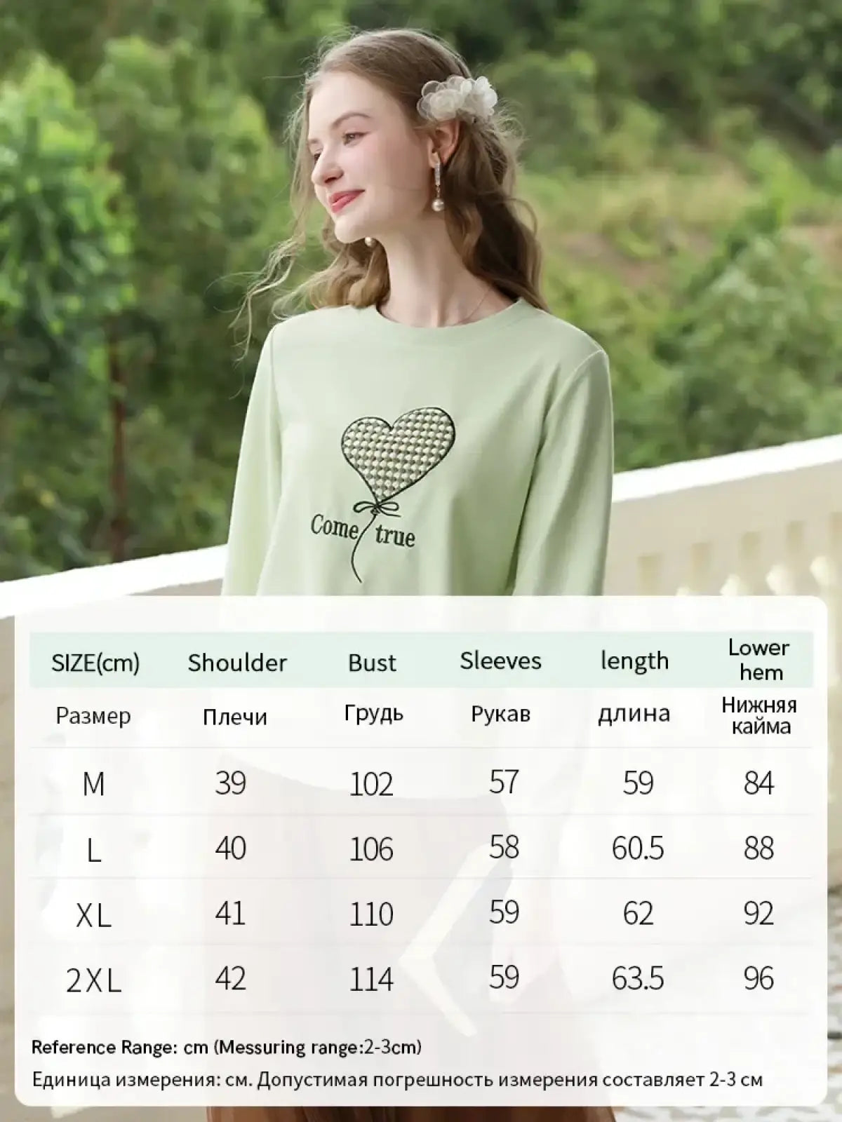 Mint green long-sleeved sweater with a black and white houndstooth heart embroidered on the front