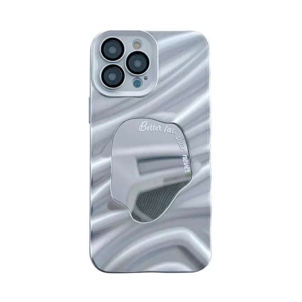 Back side of a silver mirror water ripple reflective case for iphone 14 pro max with wavy glossy texture and oval mirror inset reflecting better late than never text