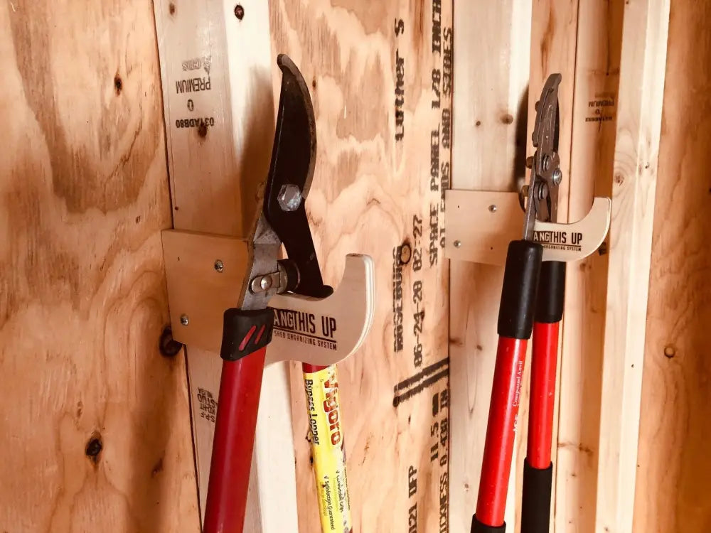 Heavy duty compact stud mounted power tool storage hook holding red handled pruning shears with black grips and metal head