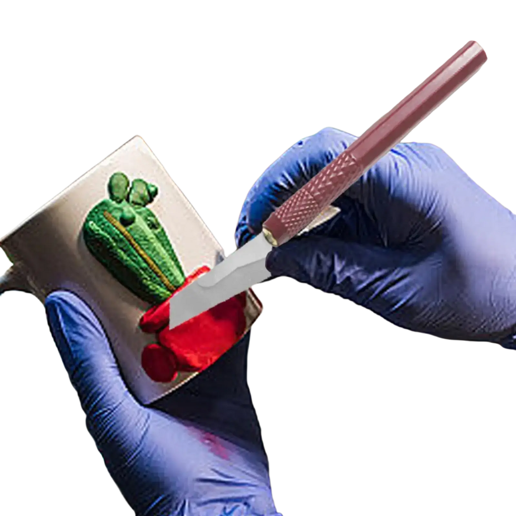 A pink-handled model craft hand saw kit knife with a metallic blade detailing a green and red cactus on a silver mug