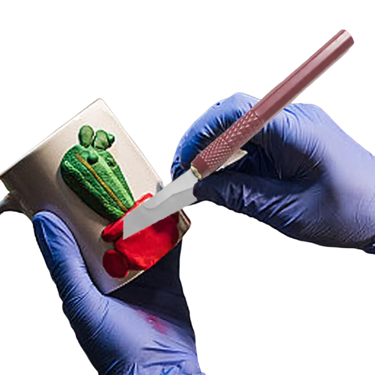 A pink-handled model craft hand saw kit knife with a metallic blade detailing a green and red cactus on a silver mug