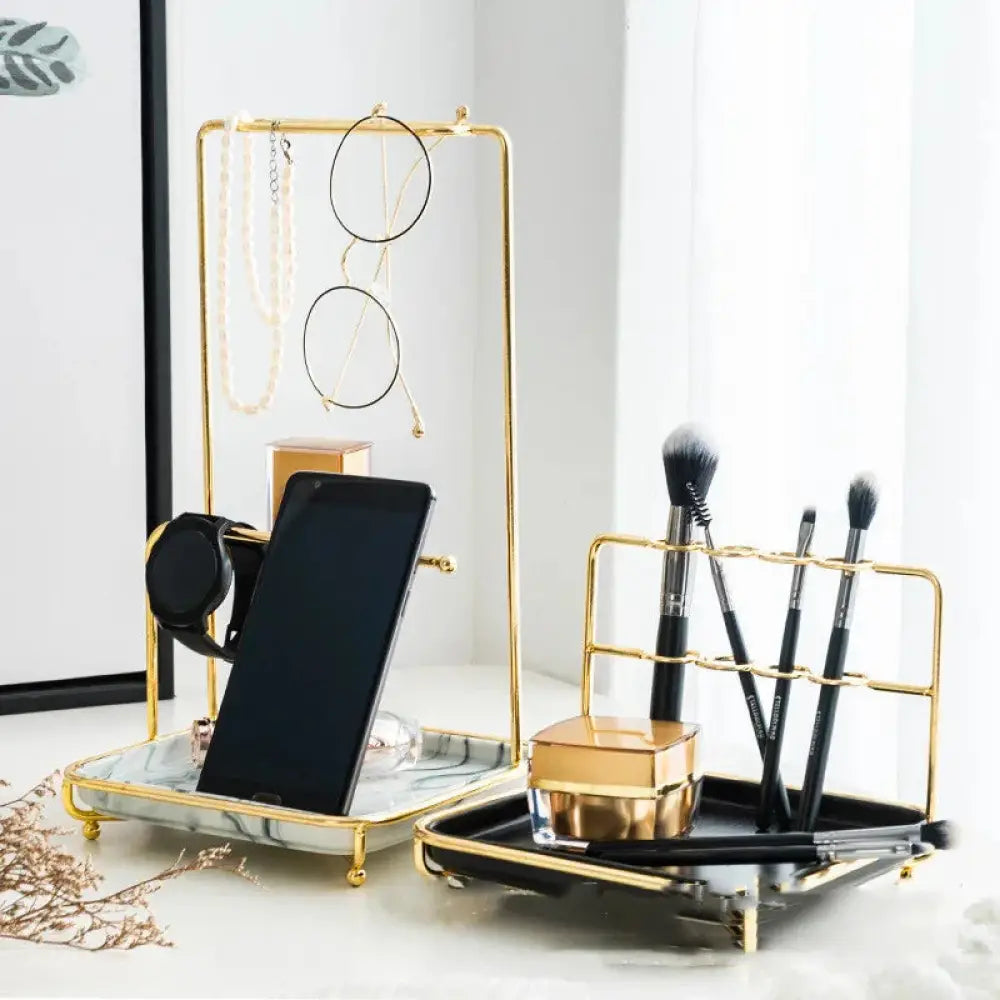 Modern gold and ceramic vanity cosmetics organizer with marble and black trays holding makeup brushes and accessories