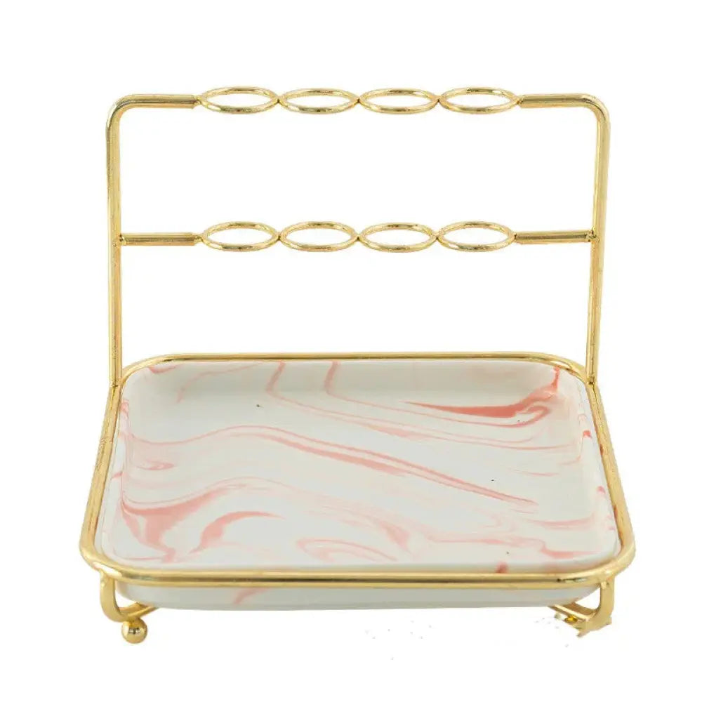 Modern gold and ceramic vanity cosmetics organizer with gold frame and pink and white marble patterned tray with oval loops