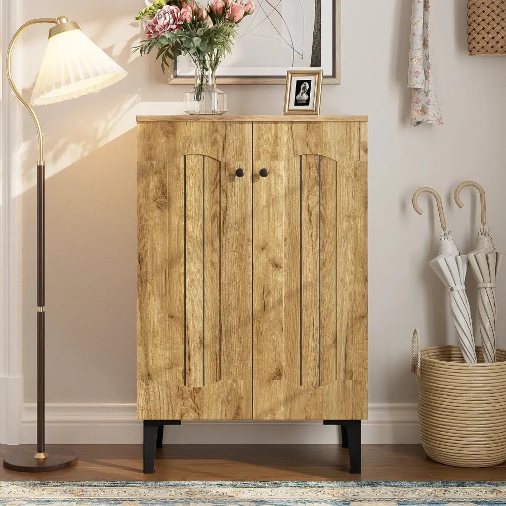 Modern light brown wooden double door shoe cabinet with black metal legs and round knobs for organized storage