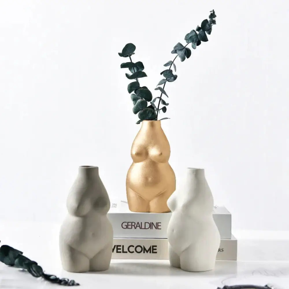 Golden ceramic vase shaped like a female torso holding dark green eucalyptus branches modern minimalist decor