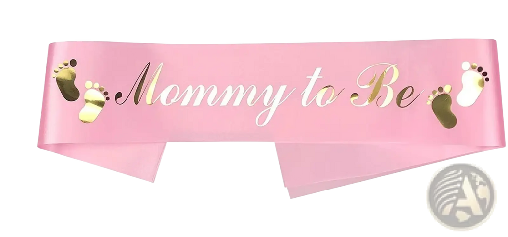 Pink satin mom to be sash with gold foil text and matching baby footprints for gender reveal kit