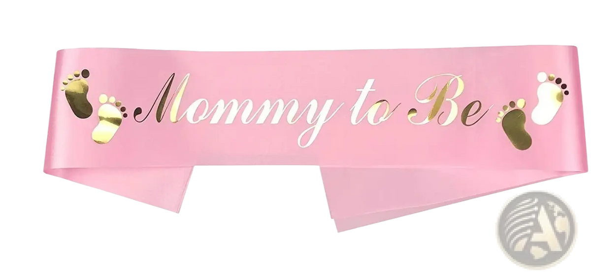 Pink satin mom to be sash with gold foil text and matching baby footprints for gender reveal kit