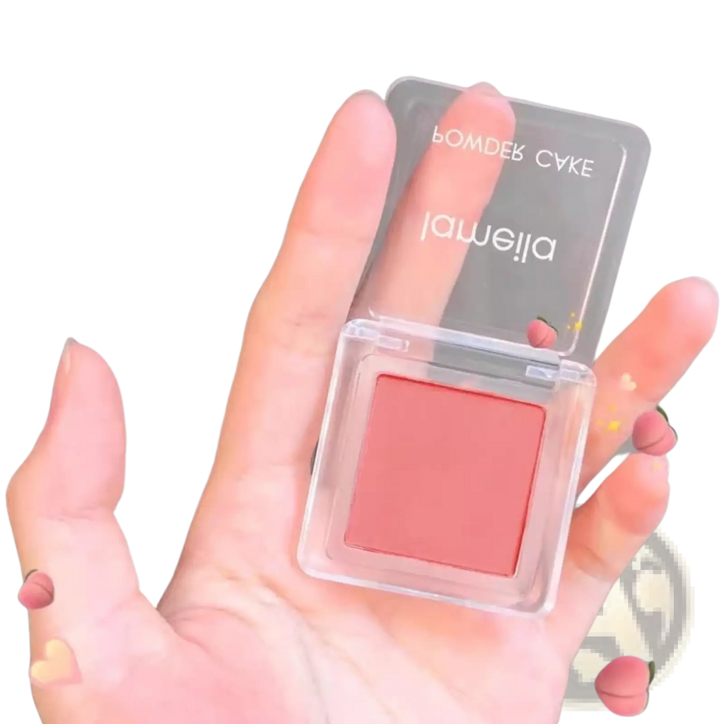 Monochrome powder blush compact with brush featuring a translucent square case and soft peachy-pink powder labeled jameilla