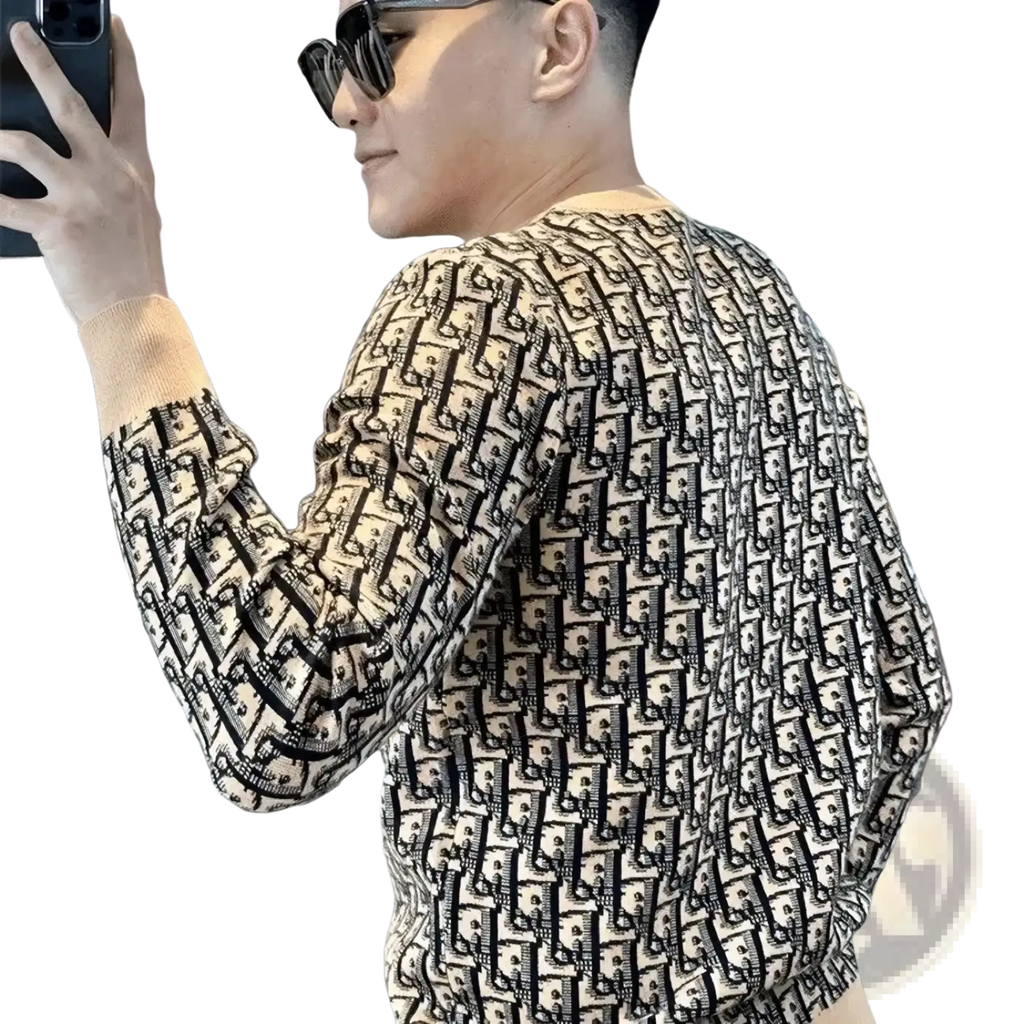 A cream-colored slim fit monogram knit pullover sweater with long sleeves and a repeating black pattern