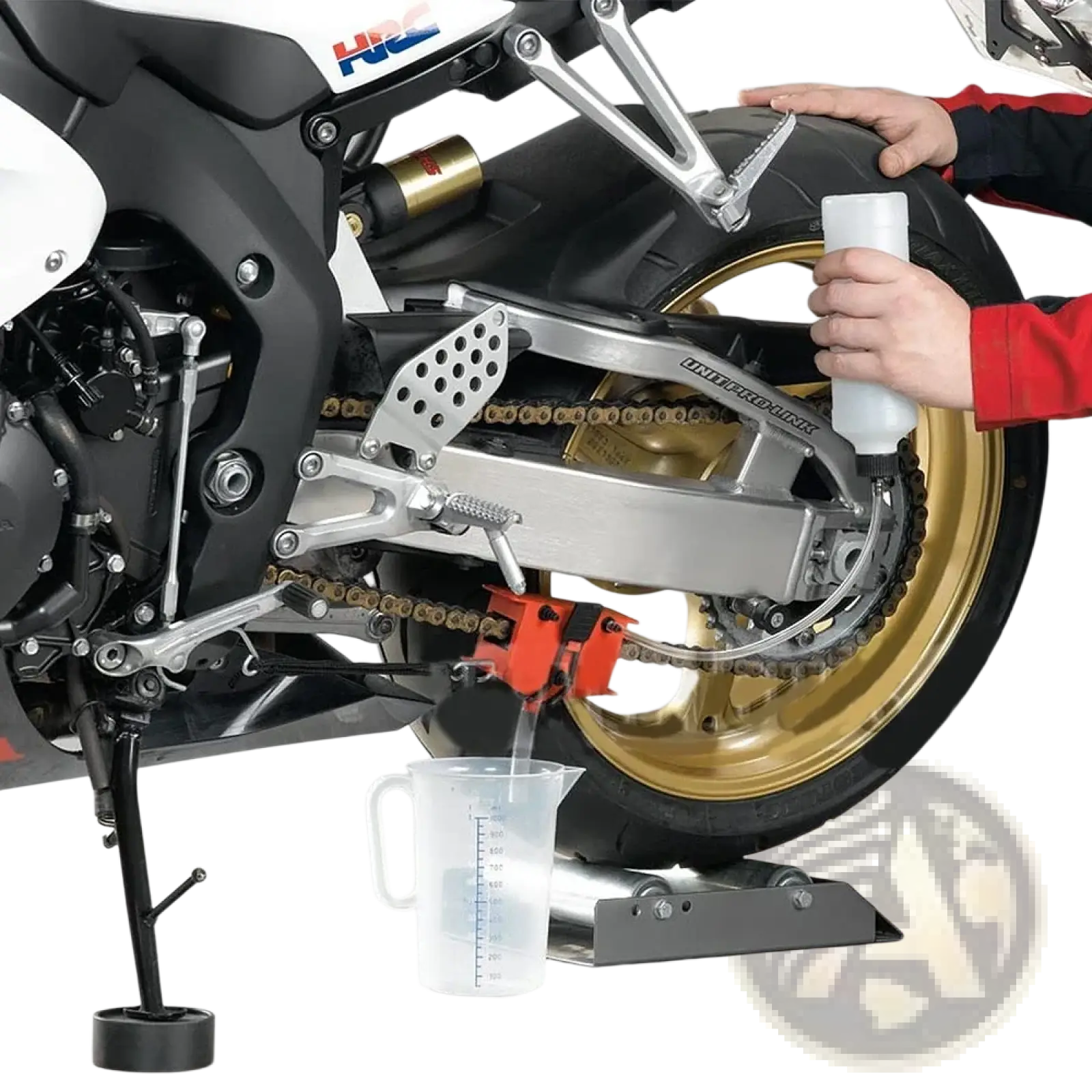 A red motorcycle chain cleaner and lube tool with a metallic handle positioned under the rear wheel