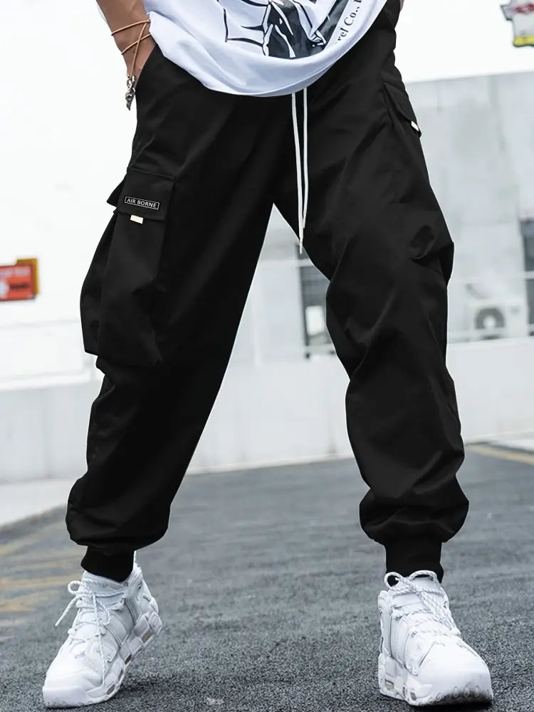 Men’s multi-pocket streetwear black cargo joggers with white drawstrings and a small thigh patch for casual use