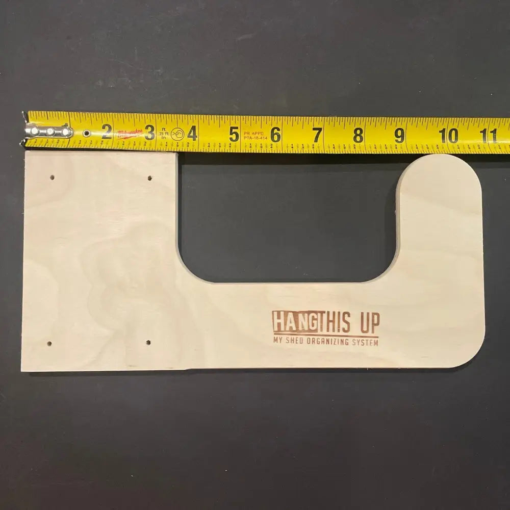 Light-colored wooden u-shaped utility storage hooks with laser-engraved hang this up logo and four pre-drilled mounting holes