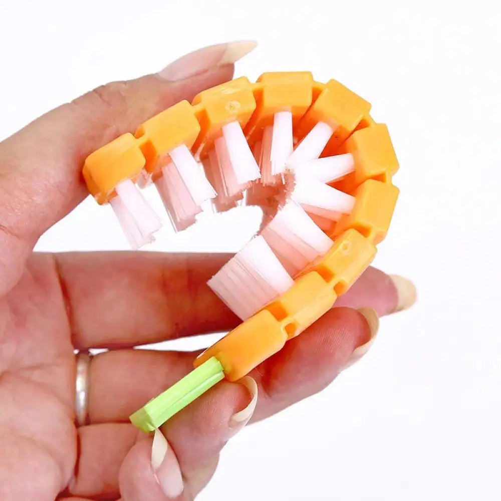 Flexible silicone vegetable and fruit cleaning brush with orange and white segmented bristles and green handle