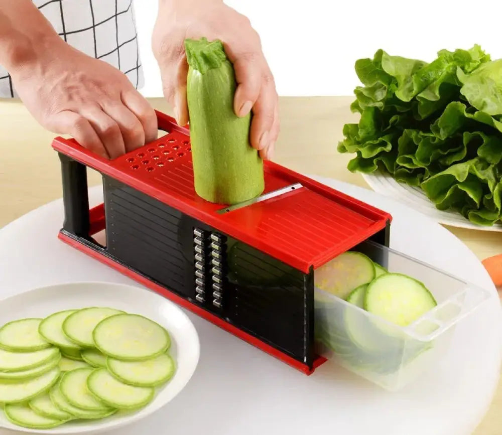 Multifunctional red and black vegetable grater and slicer set with blades and a clear plastic collection tray for efficient prep