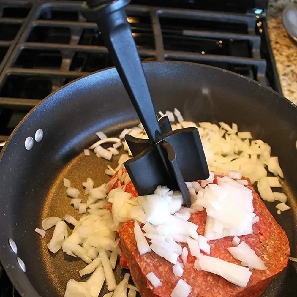 Black heat resistant nylon meat masher in a frying pan designed for chopping and mashing ground meat