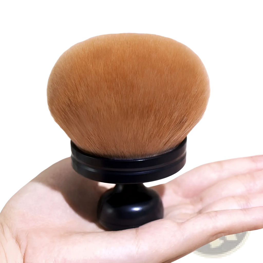 Multifunctional oversized soft powder makeup brush with plush rounded orange bristles and sleek black handle held in palm