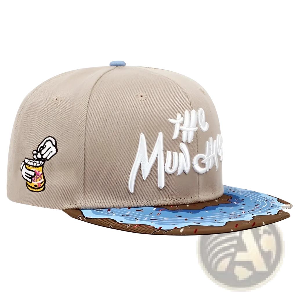 Beige flat brim snapback cap embroidered with the munchies text and cartoon patch featuring peanut butter jar and blue ice cream swirl